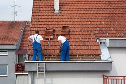 Two men performing roof repair on home